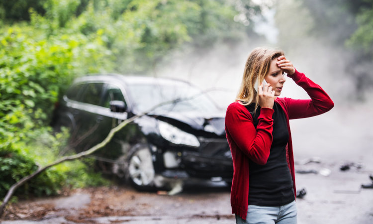 Woman with car accident in background