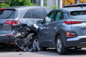 Automobile collision scene: A car impacts a parked vehicle on a residential street.
