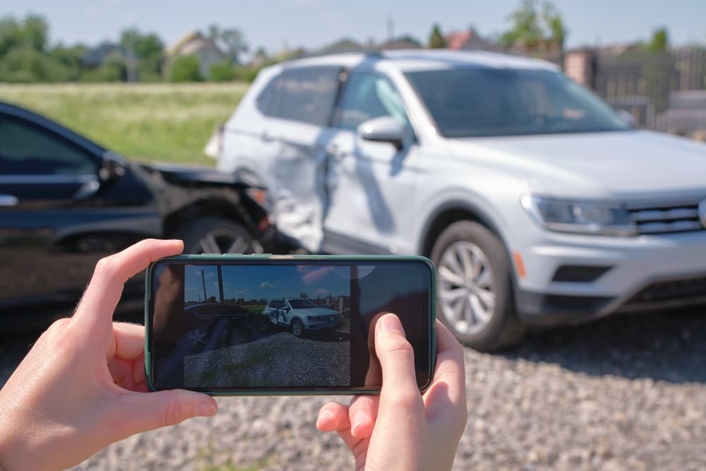 A person capturing a photo of a car accident with their camera, documenting the scene for evidence or reporting purposes
